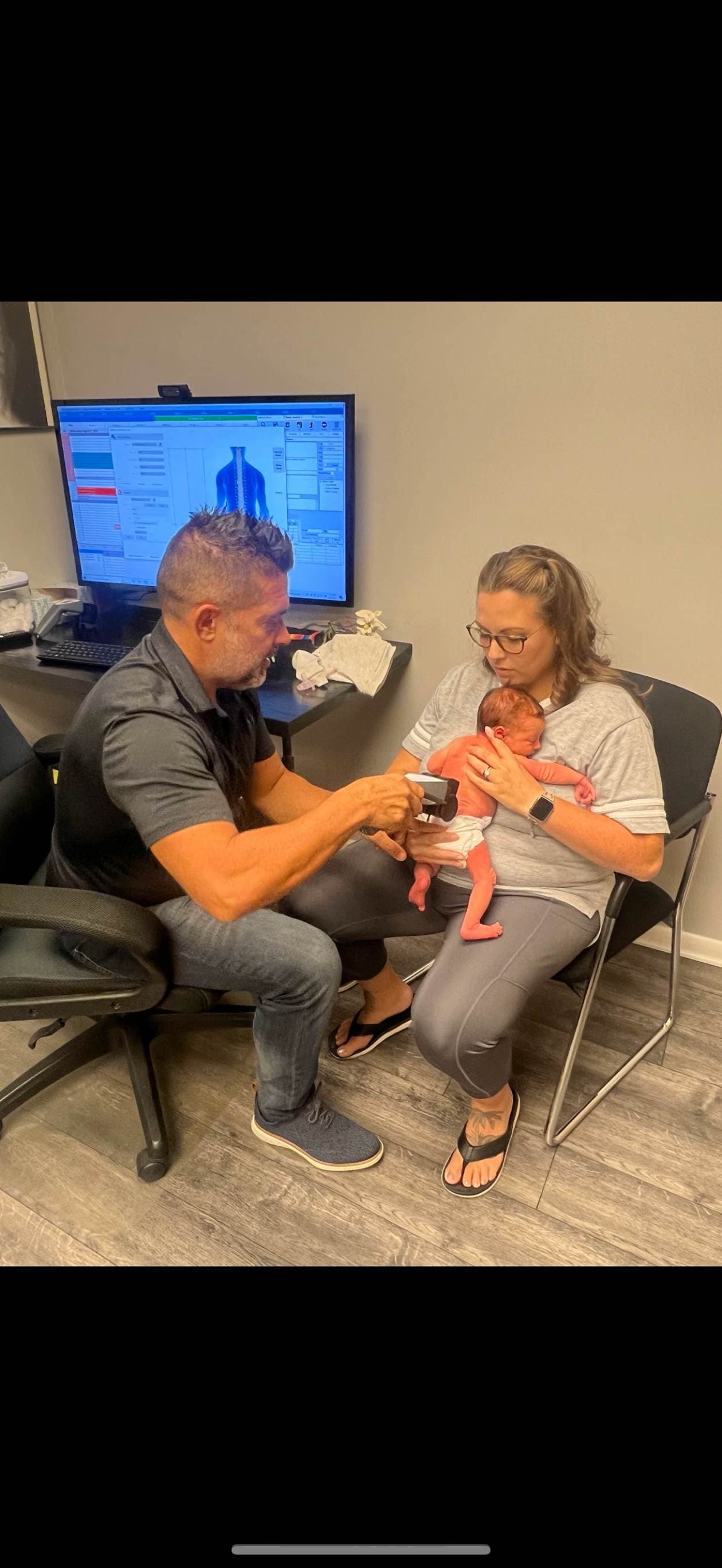 Chiropractor serving newborn with mom